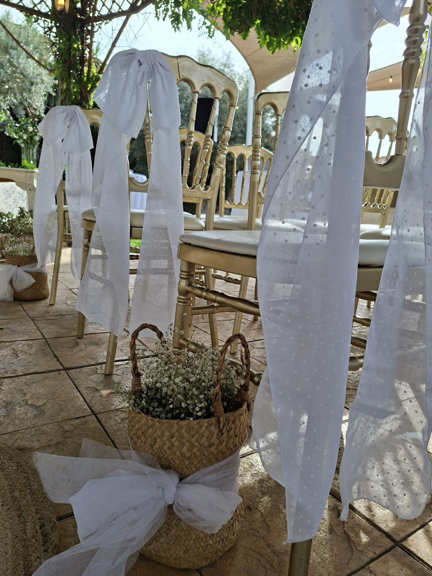 Sillas de ceremonia con lazos blancos en un jardín — Mareli Eventos Granada