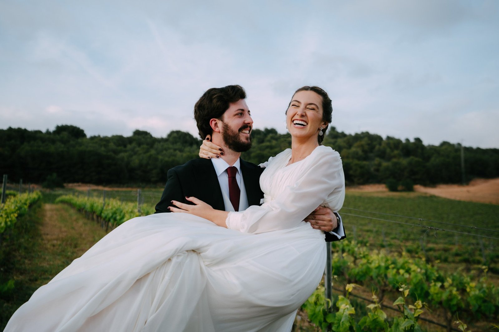 Los novios pasean entre viñedos al atardecer