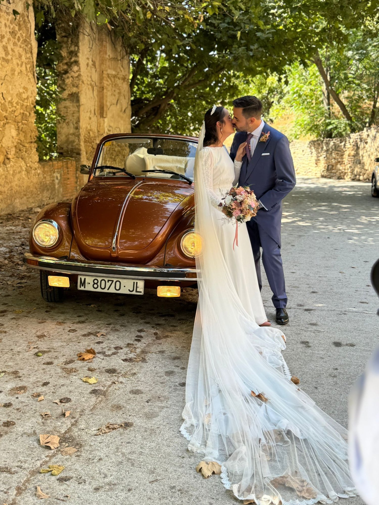 Los novios se besan junto a un Volkswagen Beetle clásico